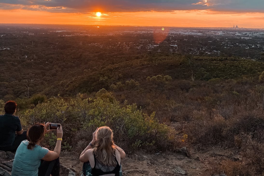 a few hikers sitting on top of a hill looking out on Perth
